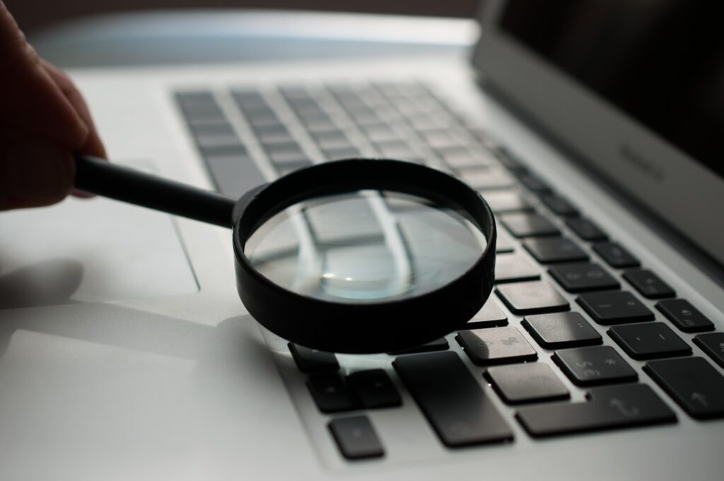 A magnifying glass resting on a laptop keyboard, emphasizing close examination