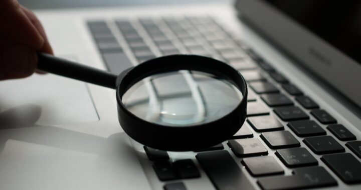 A magnifying glass resting on a laptop keyboard, emphasizing close examination